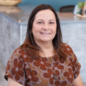 Kim wearing a top with orange flowers and smiling at the camera