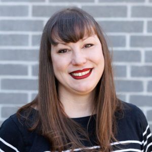 Lindsey wearing a black and white top and smiling at the camera