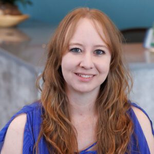 Cori wearing a royal blue top and smiling at the camera