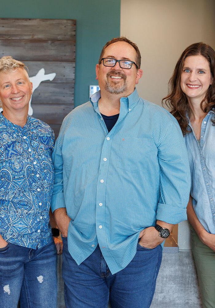 three veterinarians at Edmond East Animal Hospital posing in front of desk